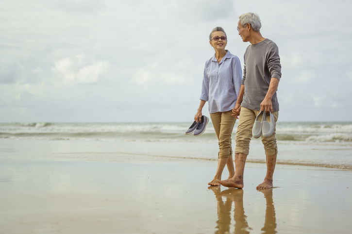 Retired couple walking along beach