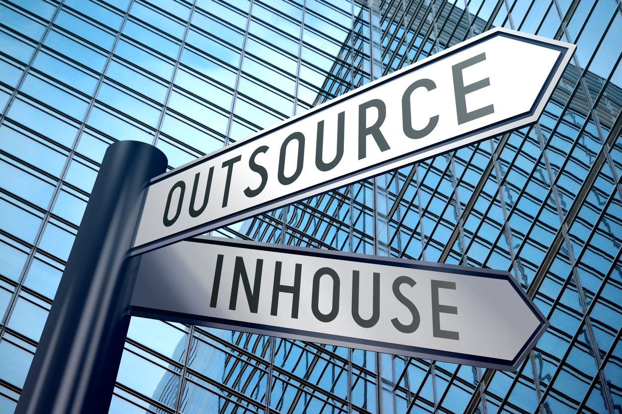 Outsource and Inhouse signpost near office building