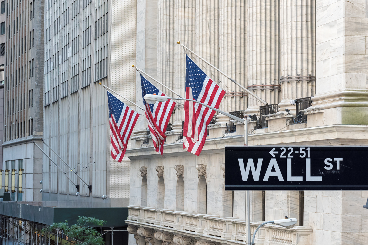 American flags on NYSE behind Wall Street sign