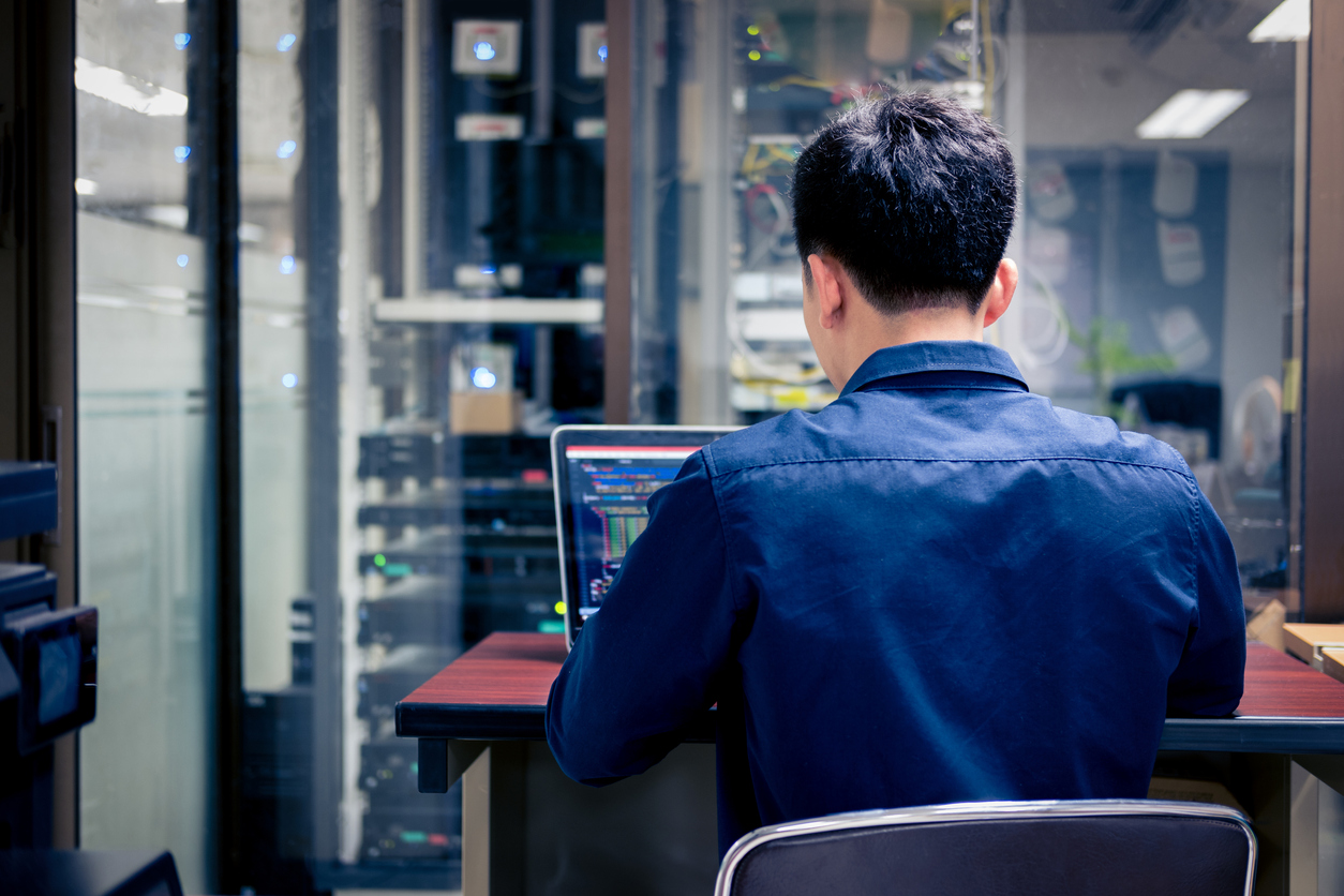 IT technician using laptop in server room