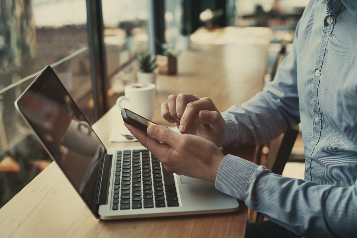 Man banking online with a smartphone and laptop