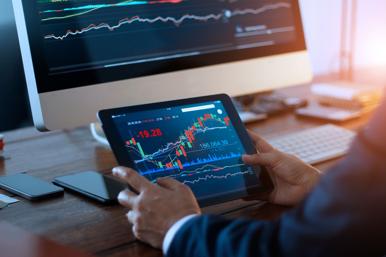 Businessman checking stocks on a computer and tablet