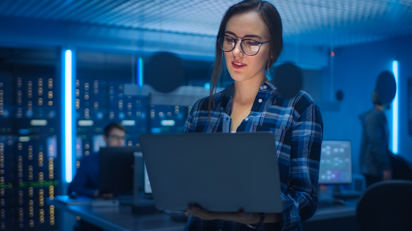 Female IT technician using laptop in a server room