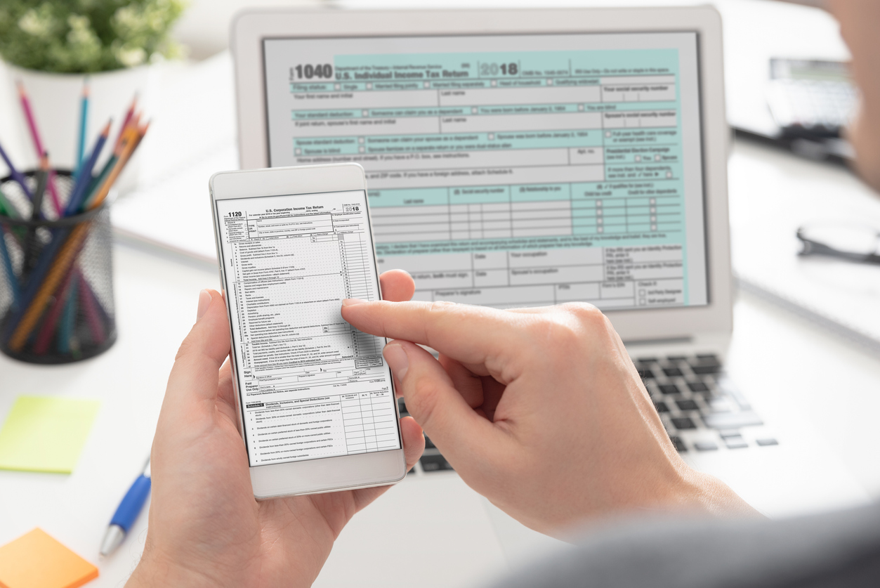 Man filing taxes on a laptop and smartphone