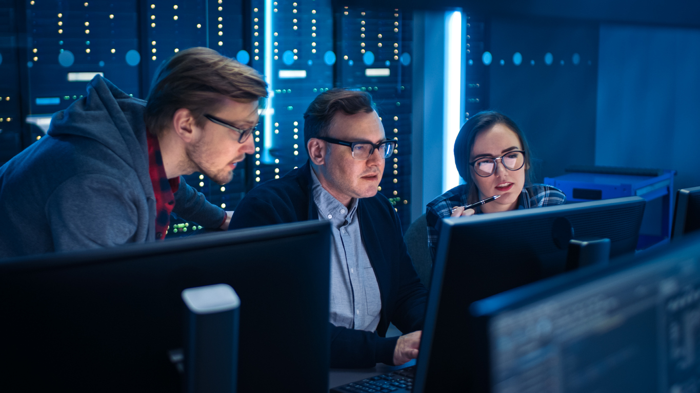 Three IT engineers looking at a computer monitor