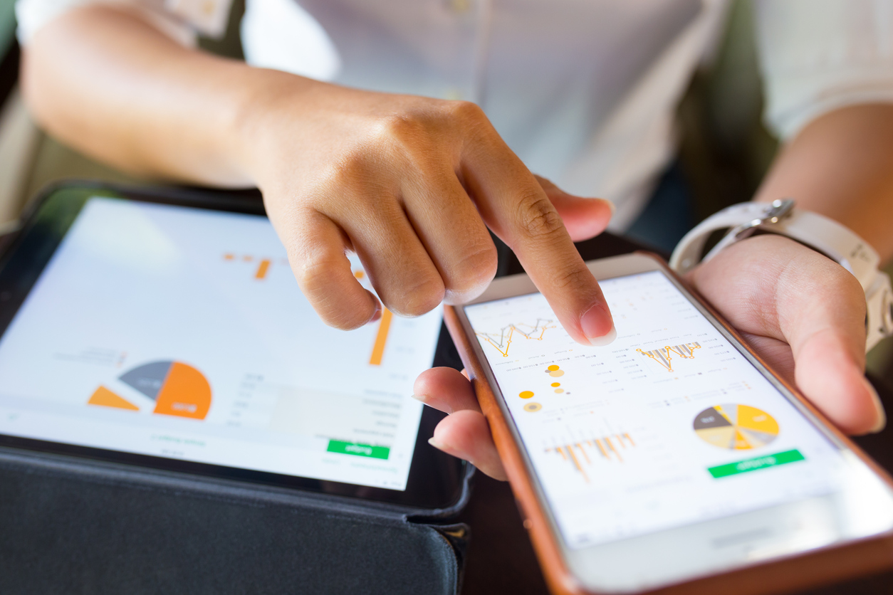 Businesswoman checking market data on a laptop and smartphone