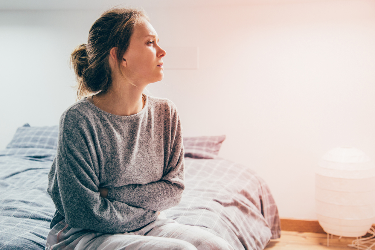 Chronically ill woman sitting on bed