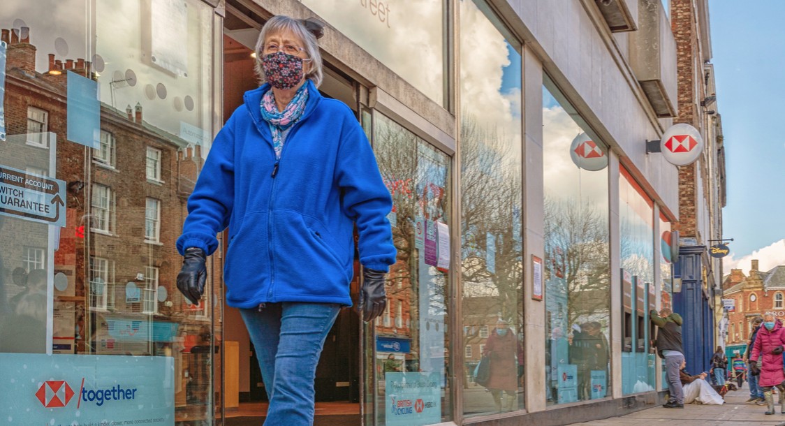 Woman in covid-19 mask and gloves outside UK bank