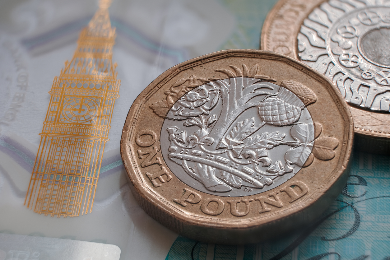 British pound coin placed on top of 5 pound banknote with visible Big Ben symbol