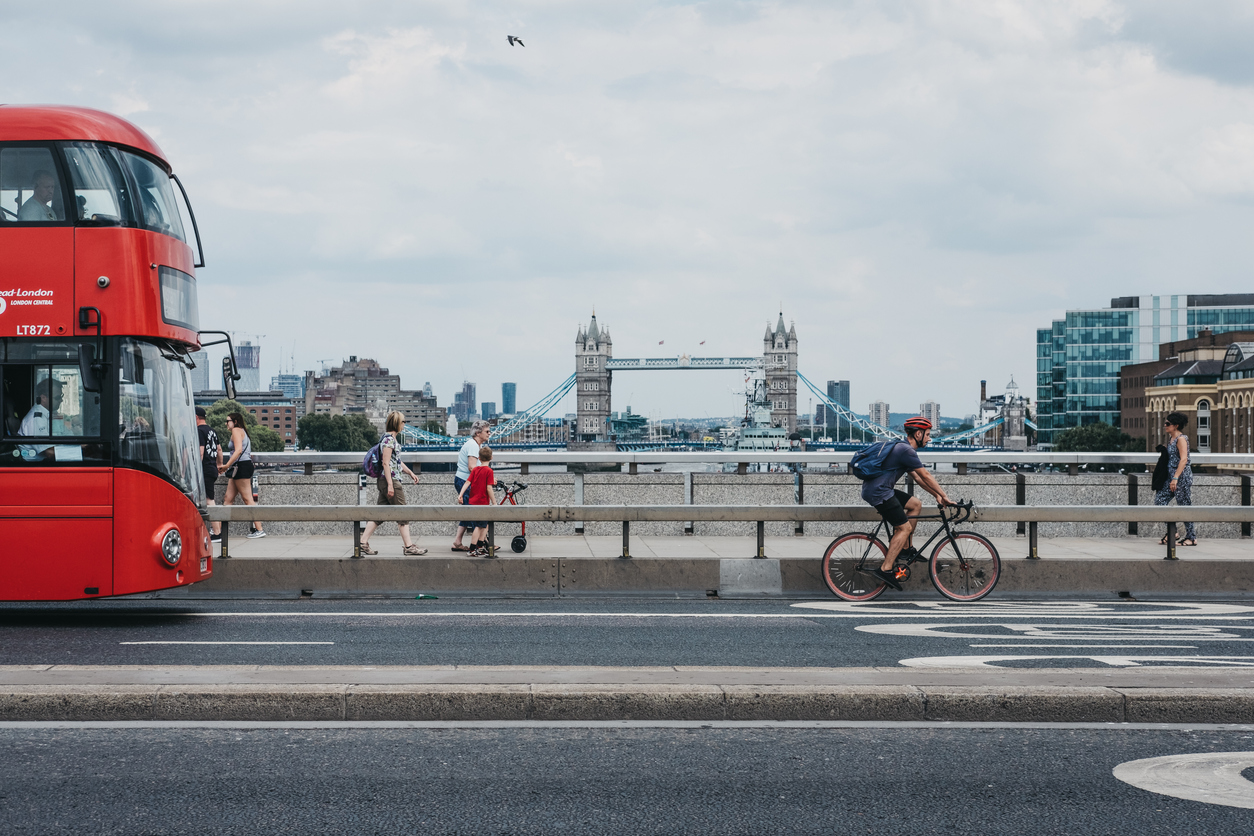 Cyclist, pedestrians and double decker bus on London Bridge, London, UK.