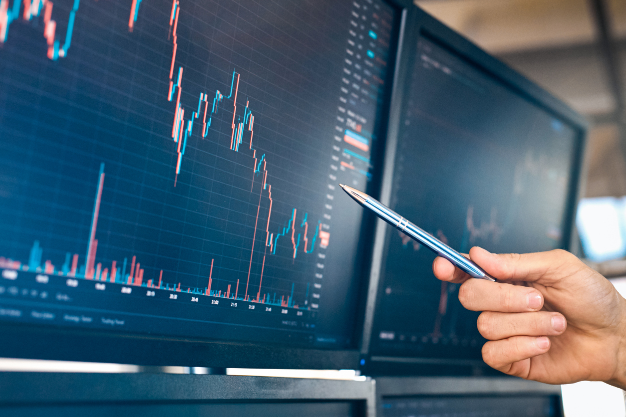 Trader sat at desk with stocks data on computer screen