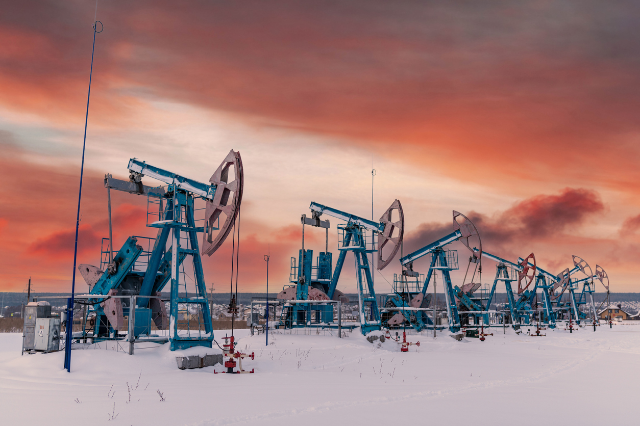 At the orange sunset dawn of the sky with clouds seven Oil pumpjack winter working. Oil rig energy industrial machine for petroleum in the sunset background for design.