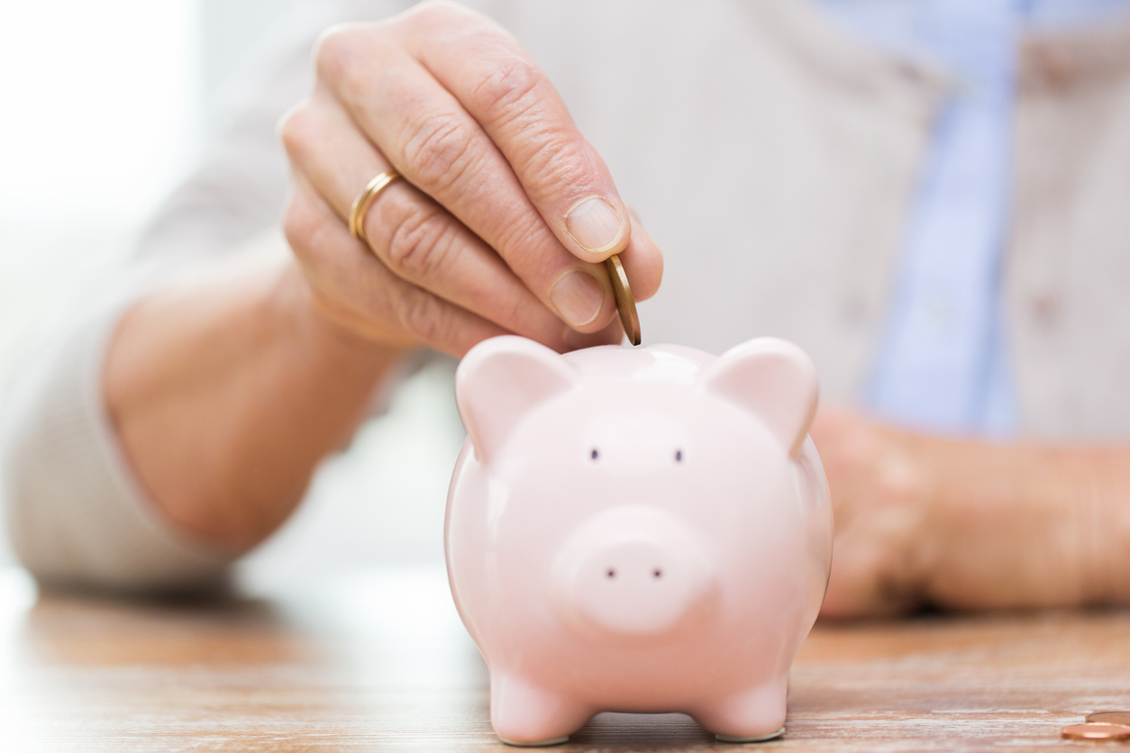 Woman putting coins into piggy bank