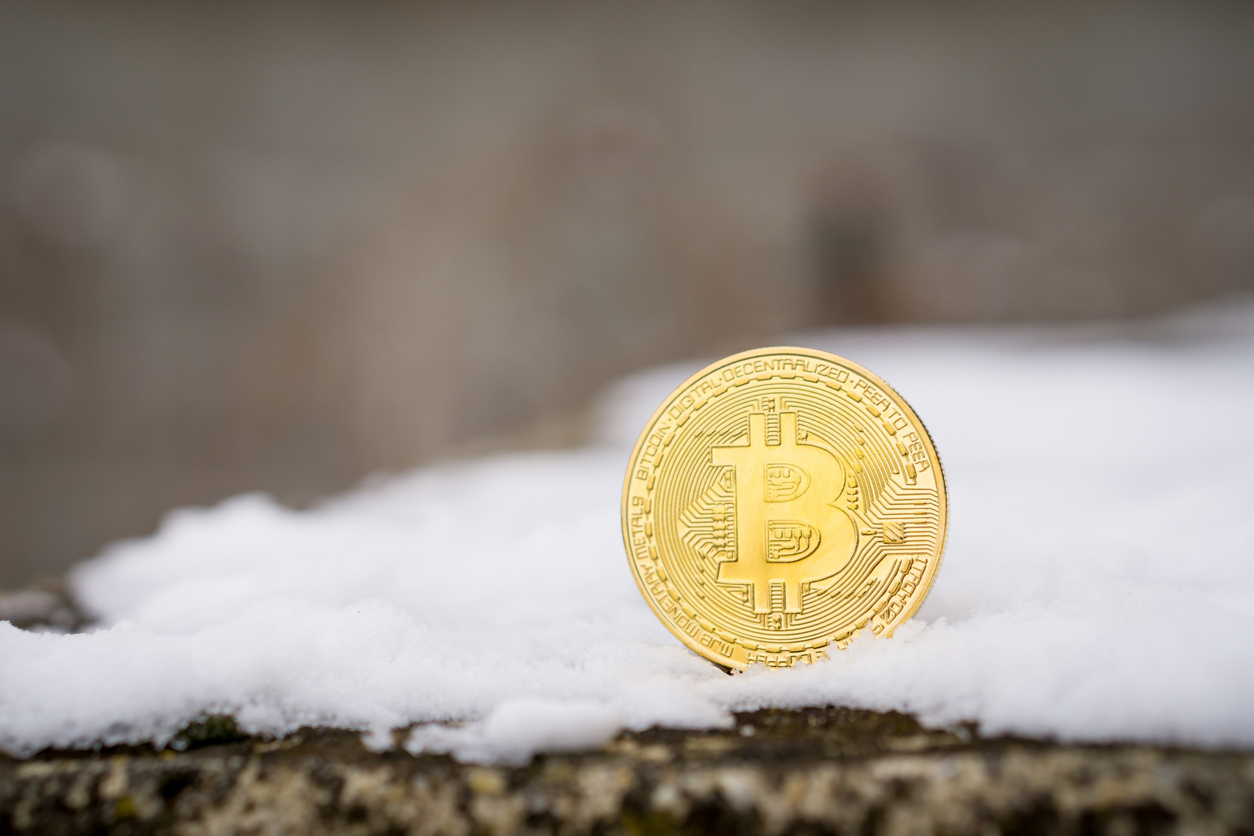 A gold Bitcoin placed in snow on concrete. Isolated scene of cryptocurrency in snow