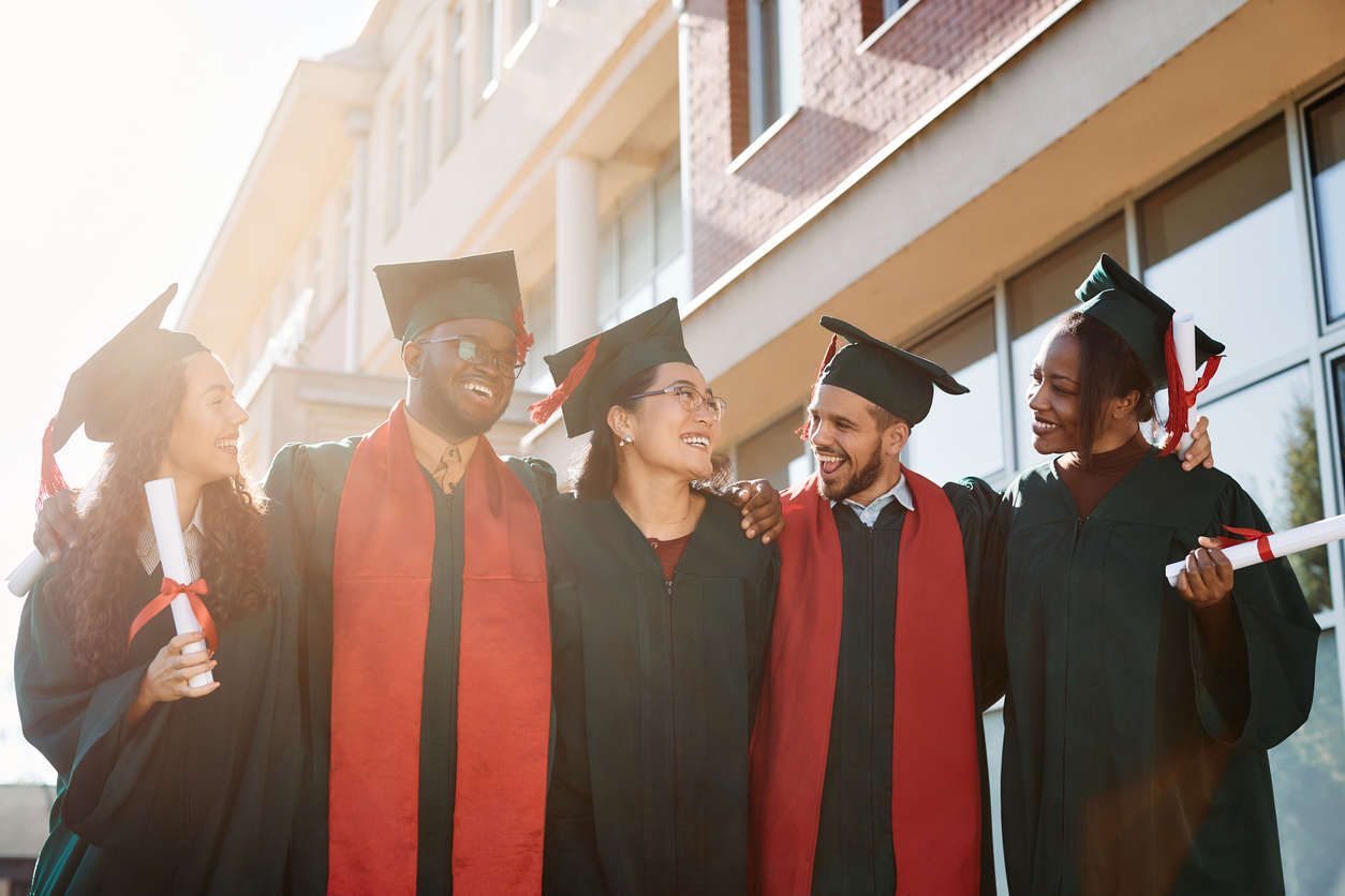 Happy group of graduate students celebrating and having fun after receiving graduation diploma.