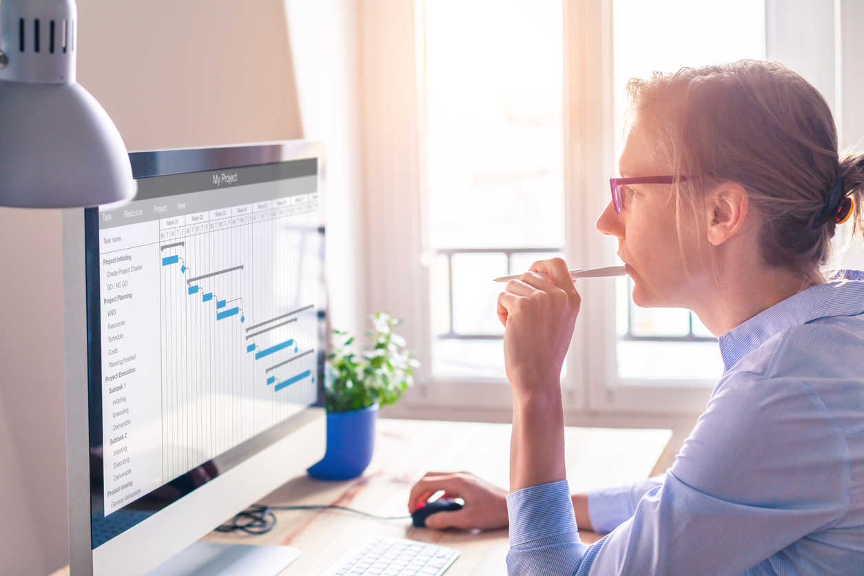 Female project manager using Gantt chart schedule to organize tasks and update planning on computer screen with software