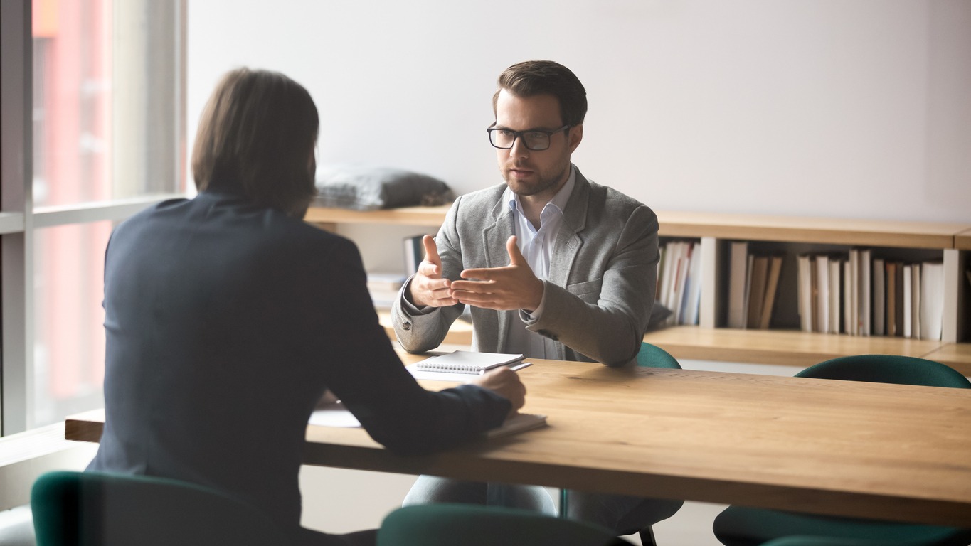 Serious businessman discussing contract details or finding problem solution with skilled financial advisor in modern office. Two successful male partners negotiation project ideas in boardroom.