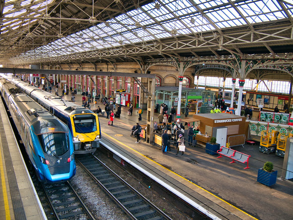 two trains at platforms in preston station in the north west of england in the uk. the architecture of the roof is visible.