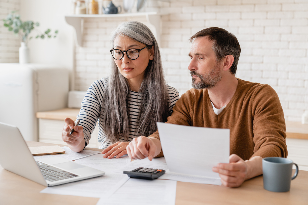 mature middle aged couple family wife and husband counting funds, savings declarations, investments,paperwork, financial documents, bankruptcy, court case, bills, pension with laptop.