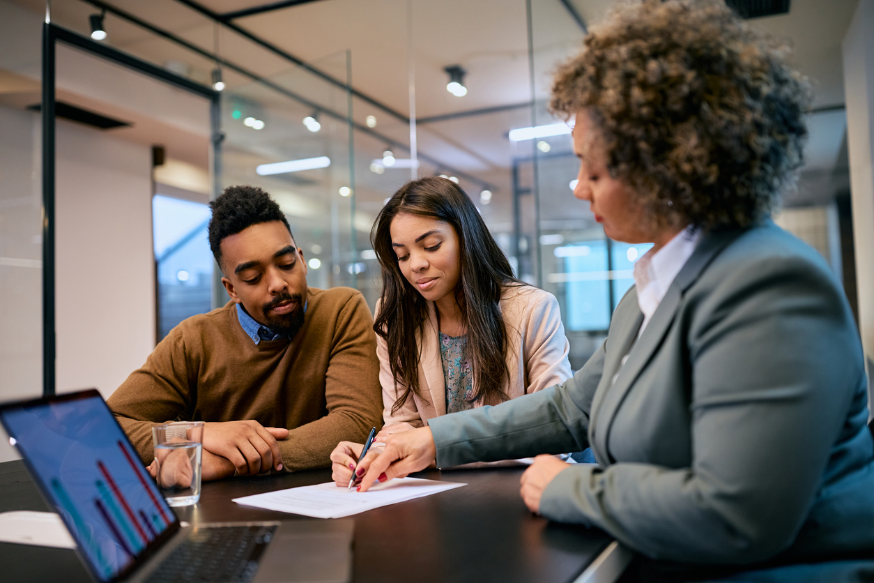 young black couple signing a contract with insurance agent in the office.