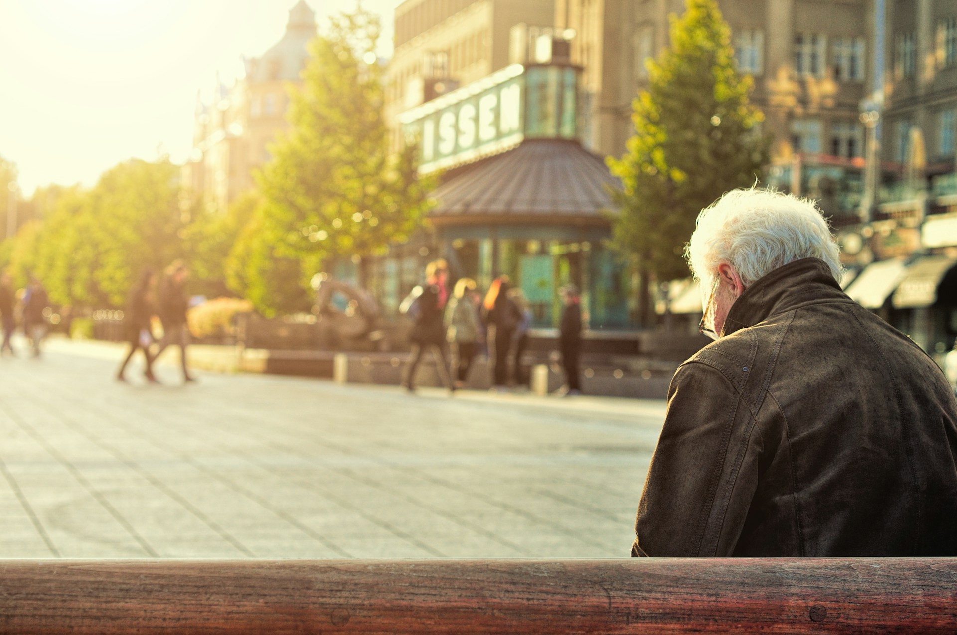 Older man sat on a bench and looking out at the rest of the town