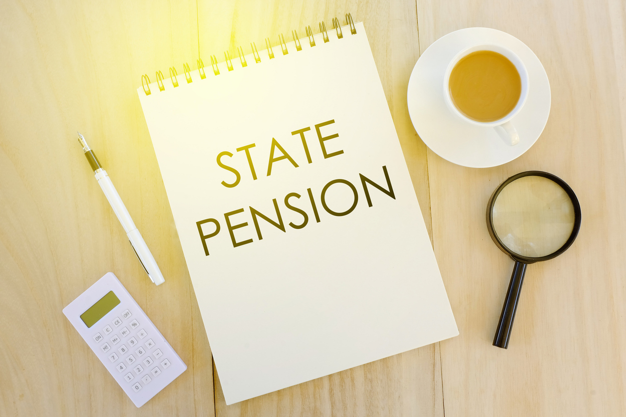 Top view of calculator,pen,magnifying glass,a cup of coffee and notebook written with State Pension on wooden background.