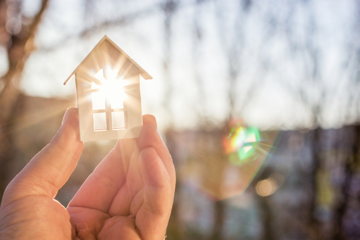 house in hand in the rays of the sun.