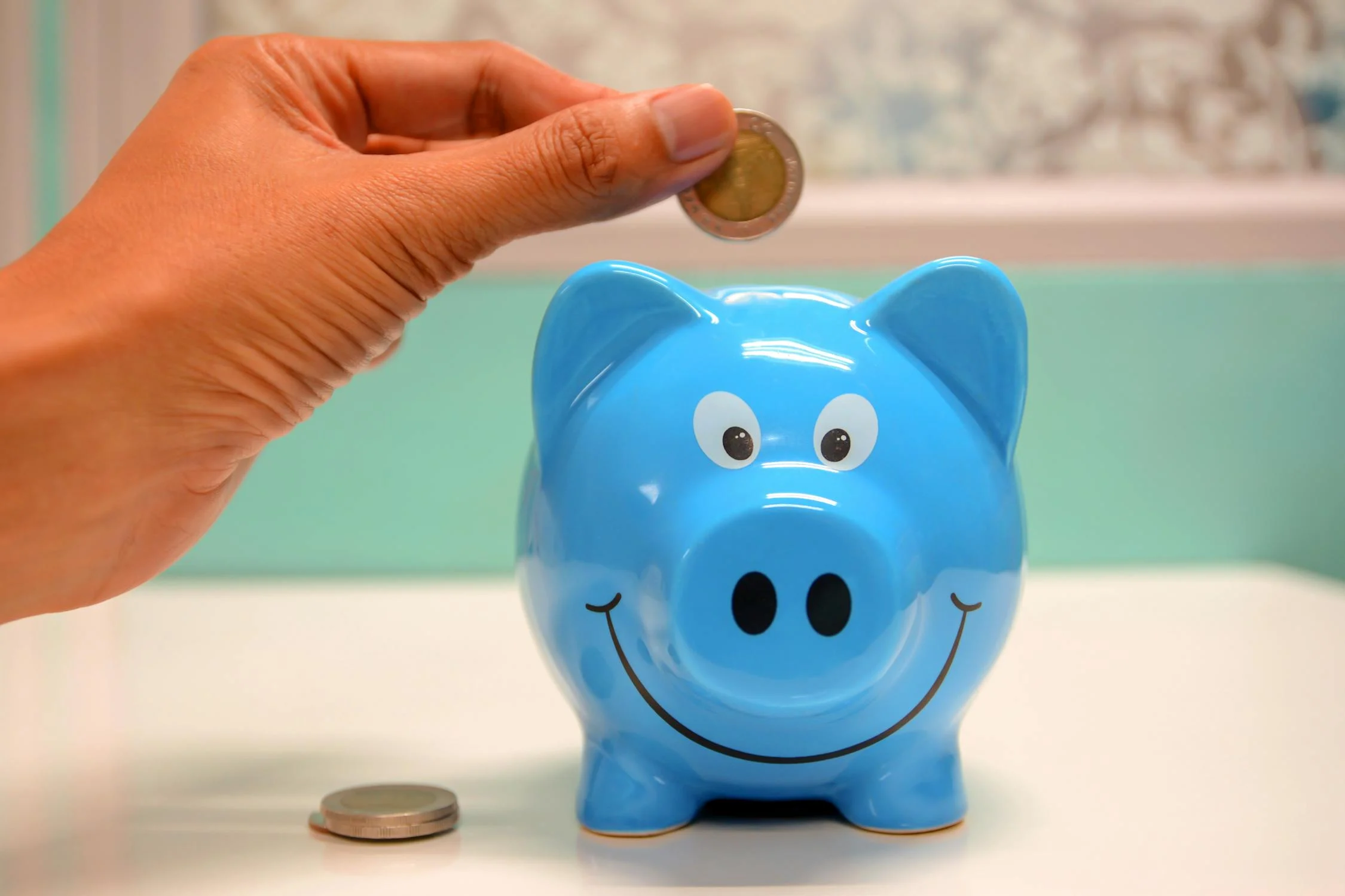 Putting money into a blue piggy bank.