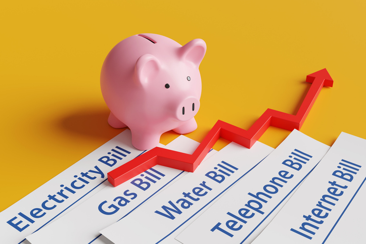 pink piggy bank, piles of utility bills and a red upward arrow on a yellow background. illustration of the concept of household expenses and increasing cost of living