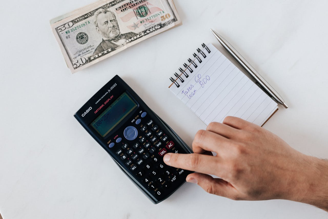 Crop faceless accountant using calculator while making budget