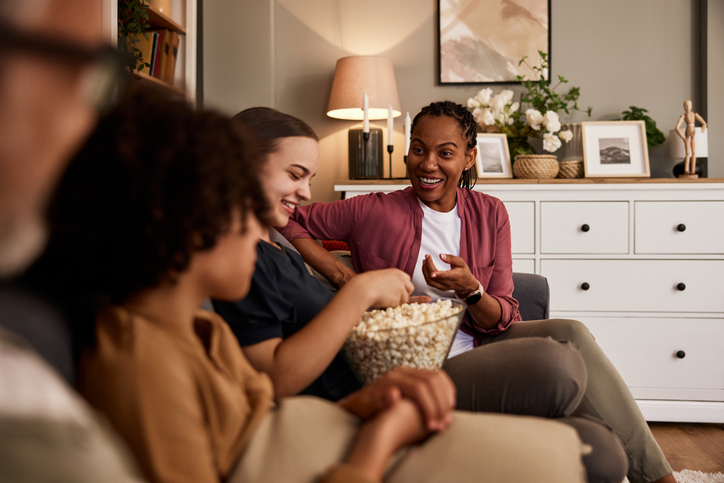 a beautiful african woman talking with friends and snacking popcorn.