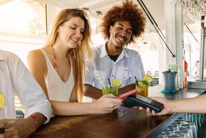 young couple using credit card for payment at beach bar