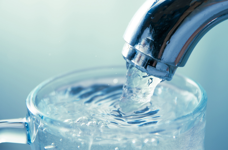 close up view of water flowing from tap into glass