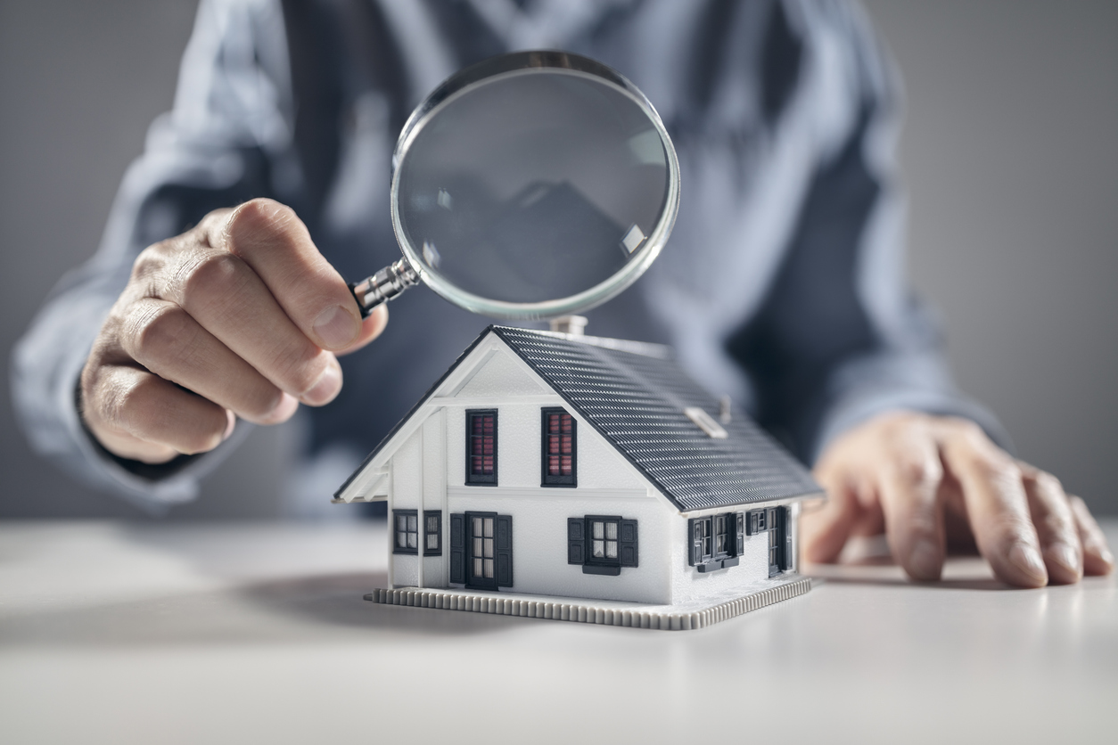 House with ith man holding magnifying glass concept for home appraisal