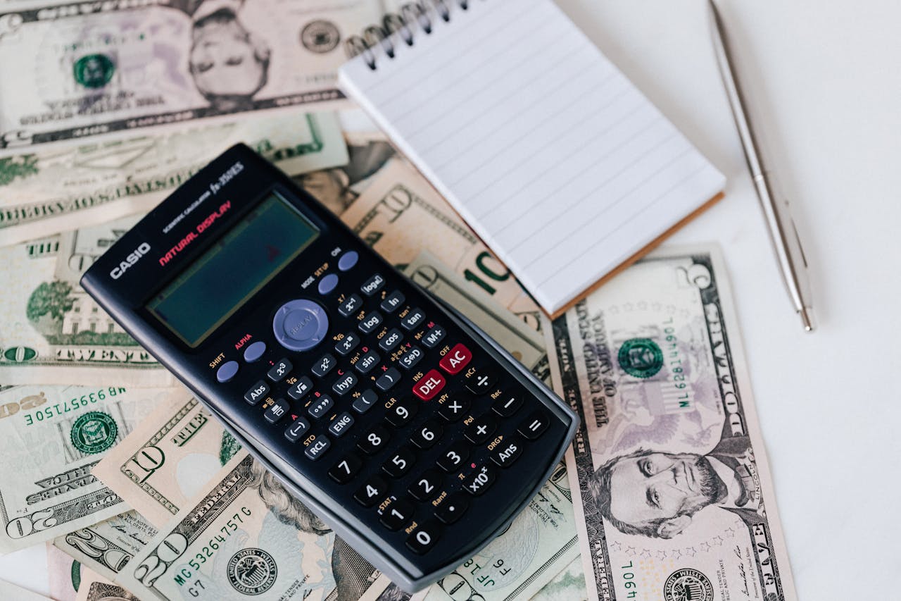 Calculator and notepad placed on USA dollars stack