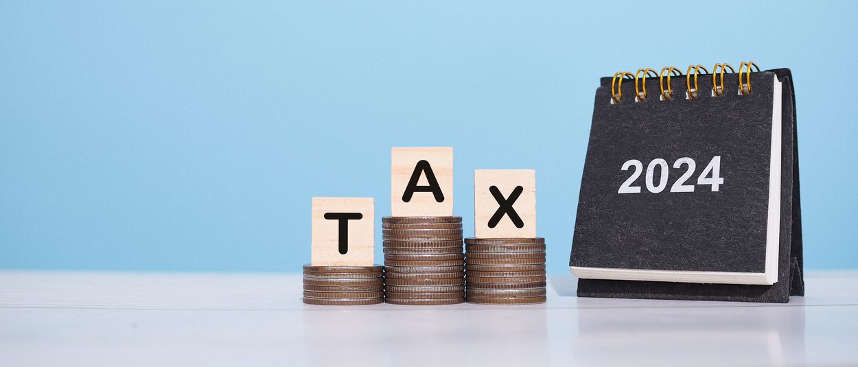 2024 desk calendar and wooden block with word tax on stack of coins. the concept of saving money for payment tax, financial, investment and business growing in year 2024.