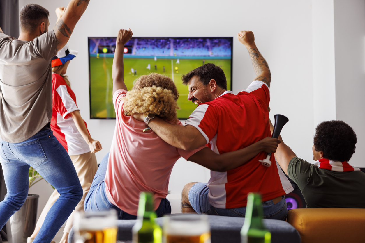 friends cheering while watching football on tv