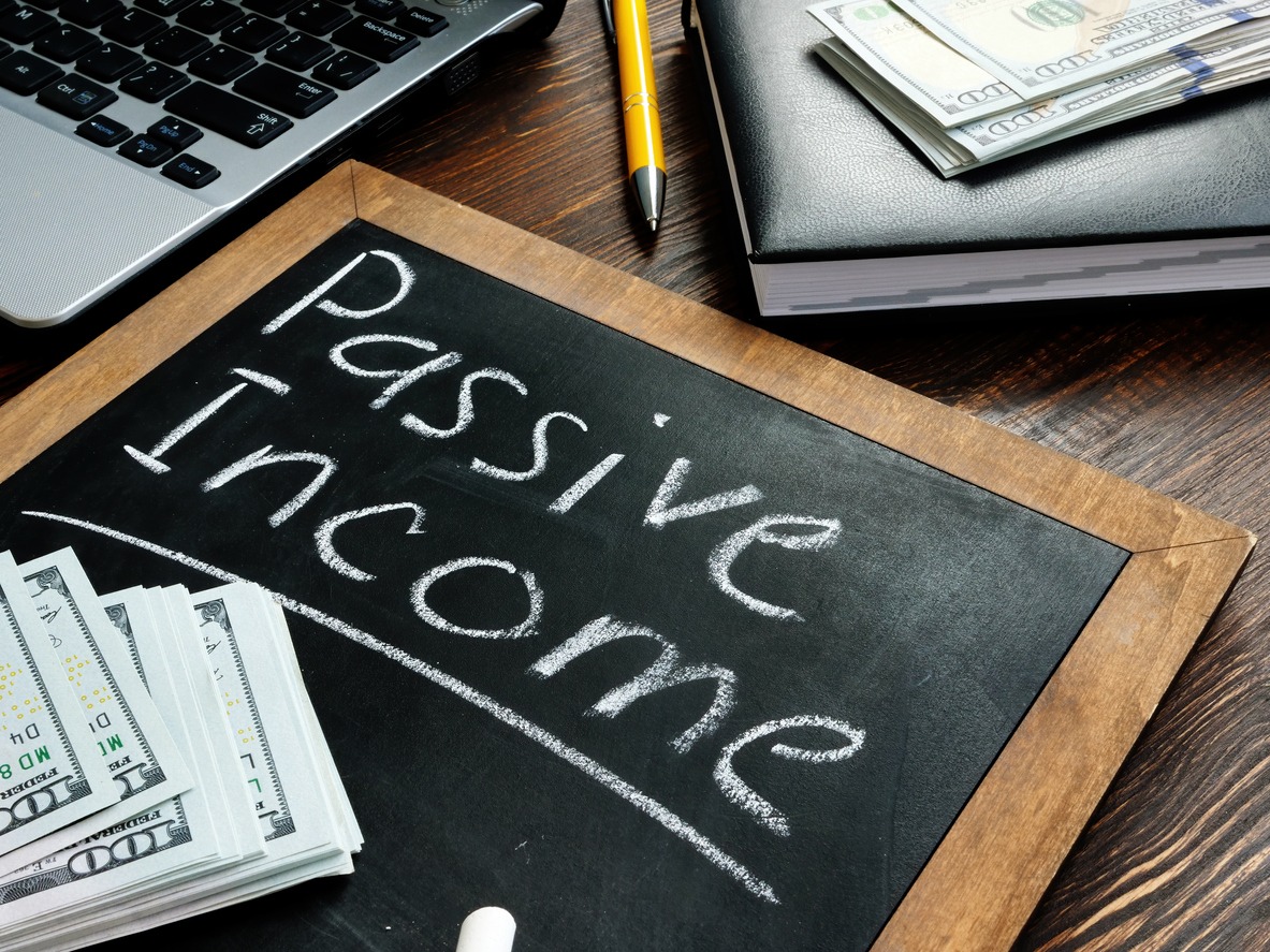 passive income inscription on the board and a bundle of bills.