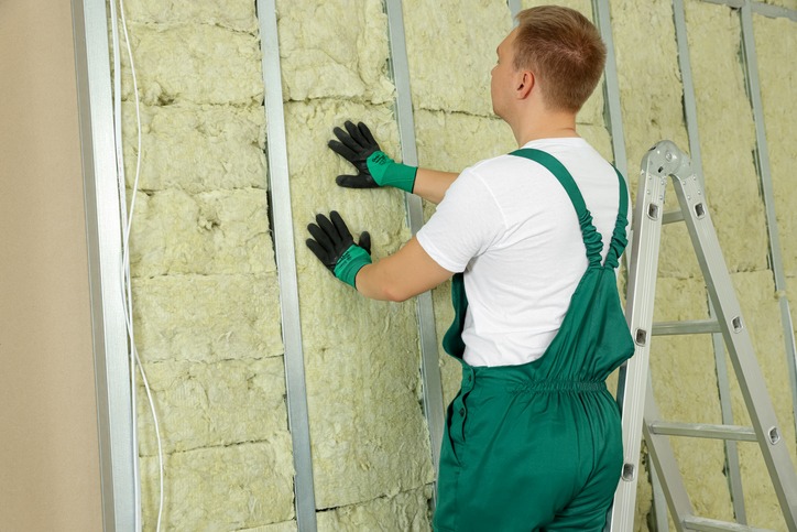 worker installing thermal insulation material on wall indoors