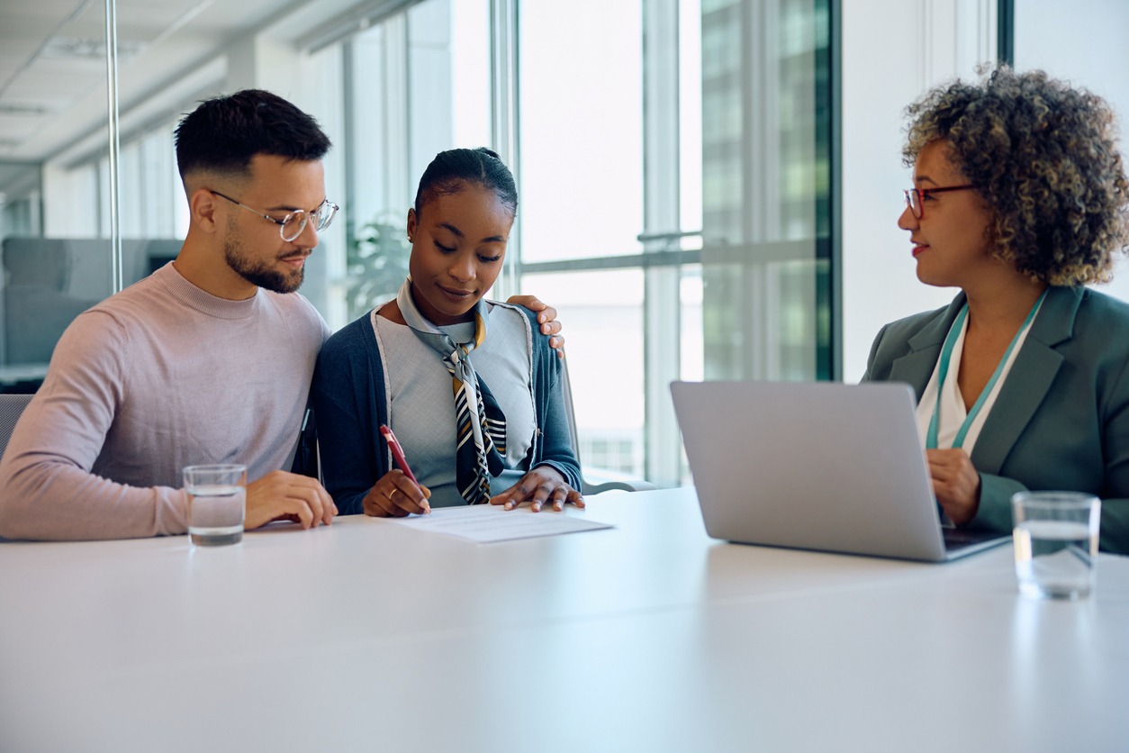 young couple signing a contract with real estate agent in the office.