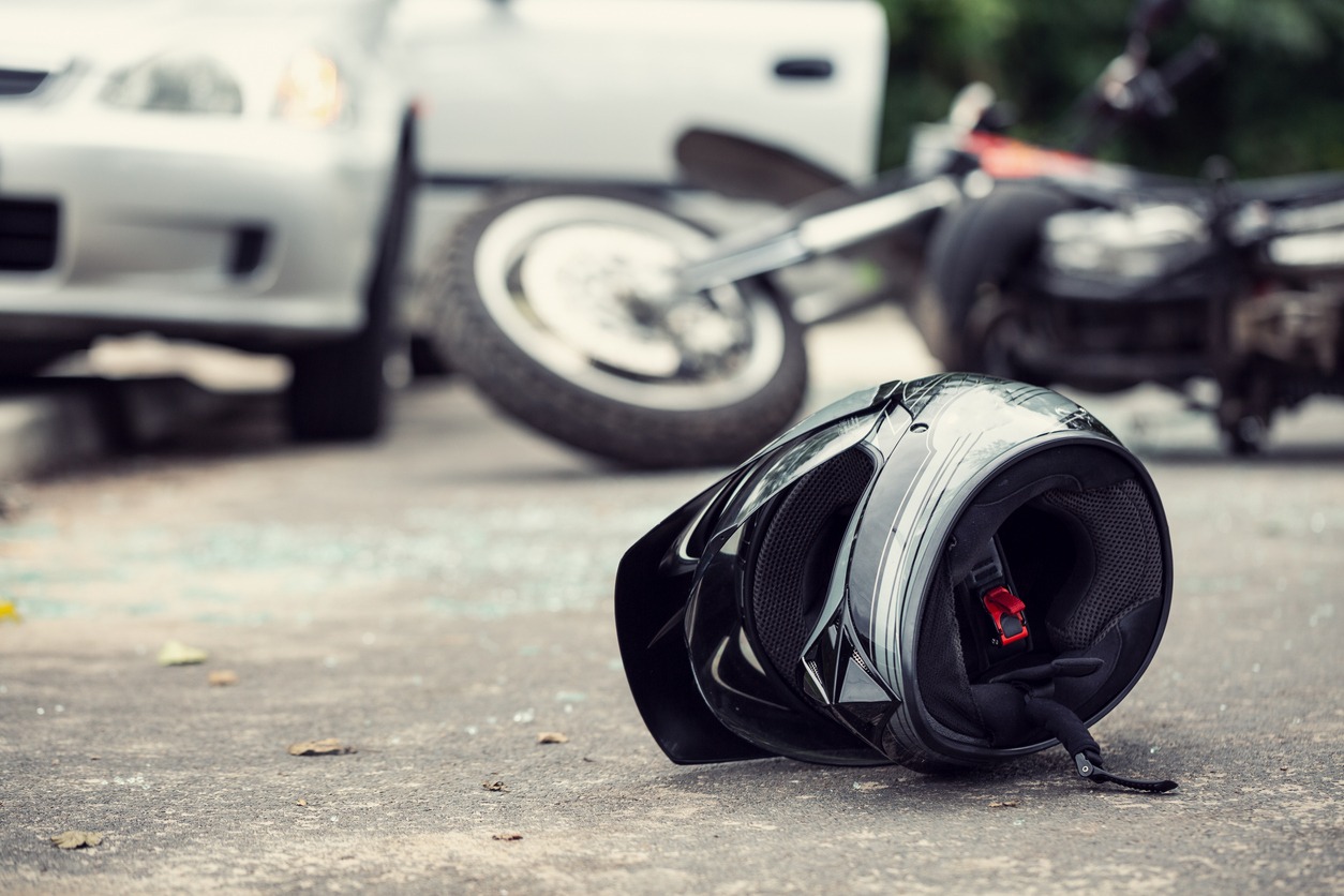 close up of a helmet of a driver with a blurred motorbike and car in the background