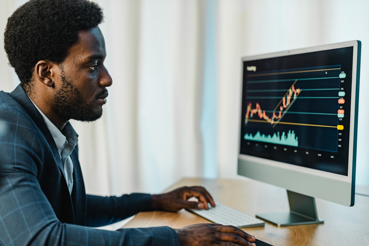 focused black male broker using computer for trading