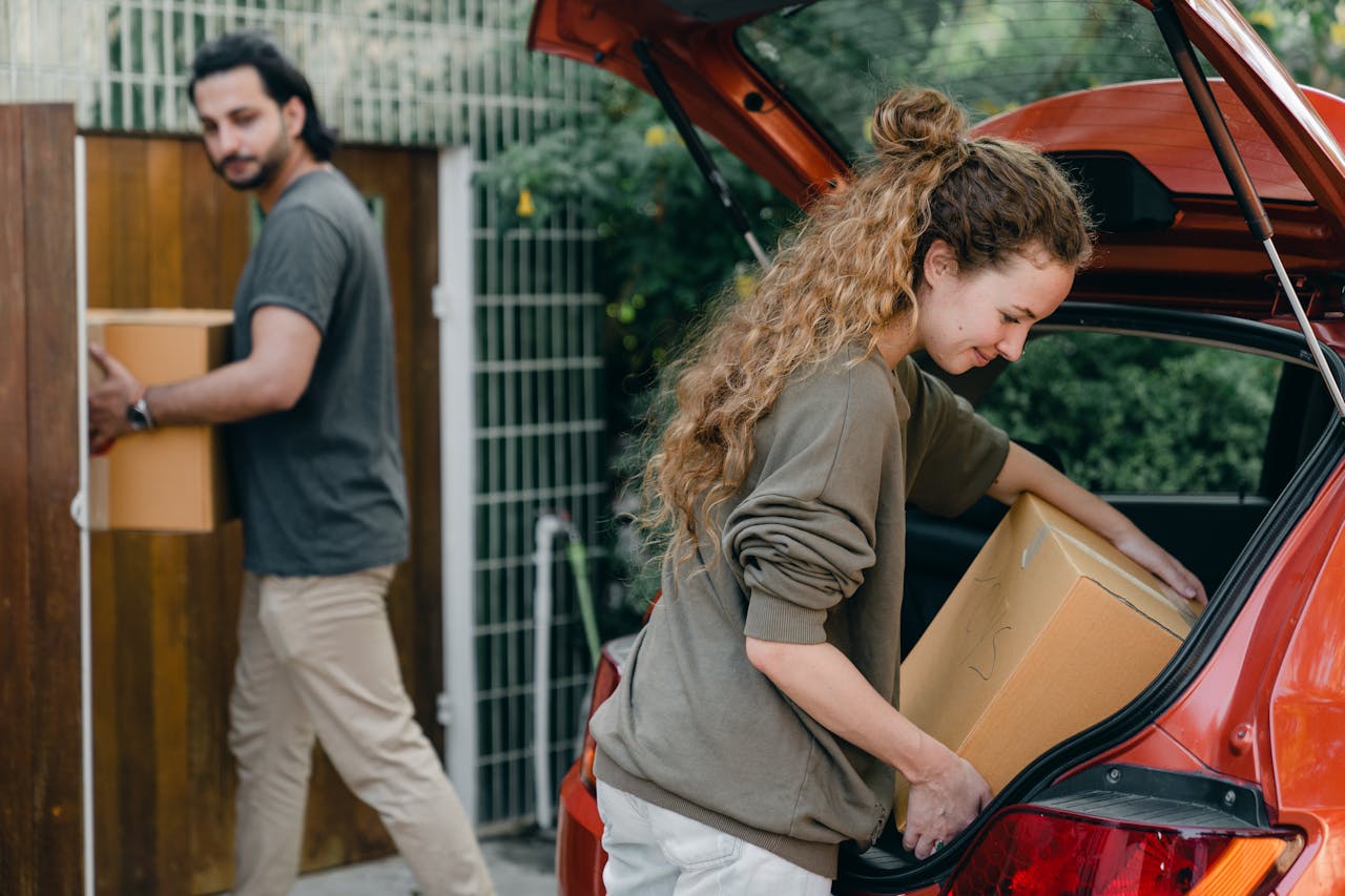 A couple putting their things in a red car.