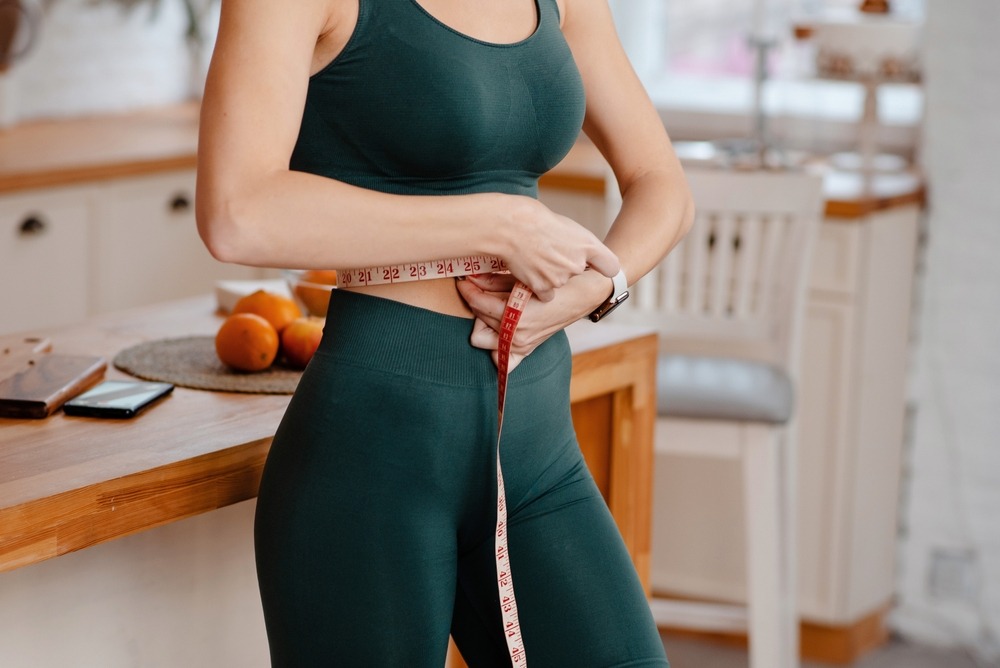 cropped,view,of,the,sporty,woman,measuring,waist,with,tape