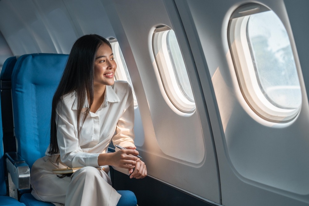 asian,woman,sitting,in,a,seat,in,airplane,and,looking