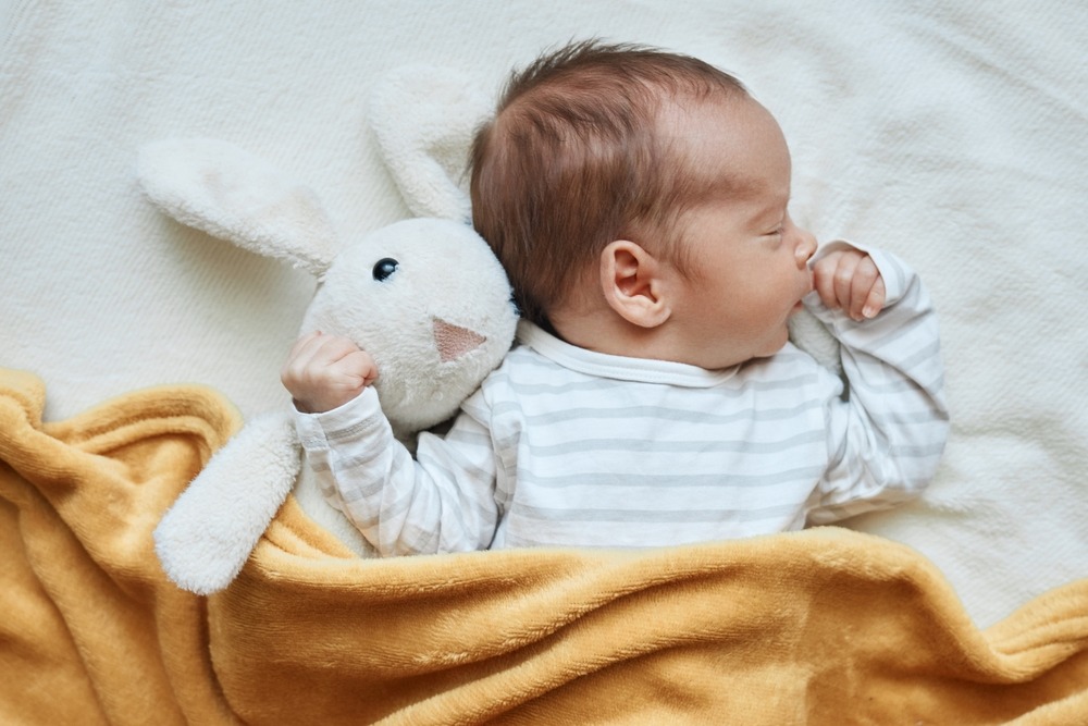 newborn,baby,boy,in,bed,sleeping,under,yellow,soft,blanket