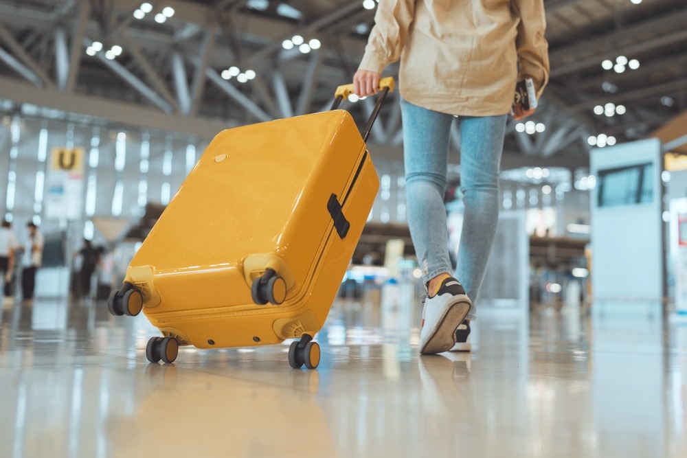 female,traveler,passenger,walking,with,a,yellow,suitcase,at,the