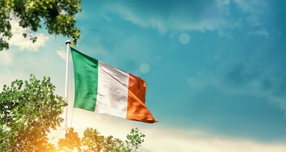 ireland,national,flag,waving,in,the,sky,behind,the,tree.