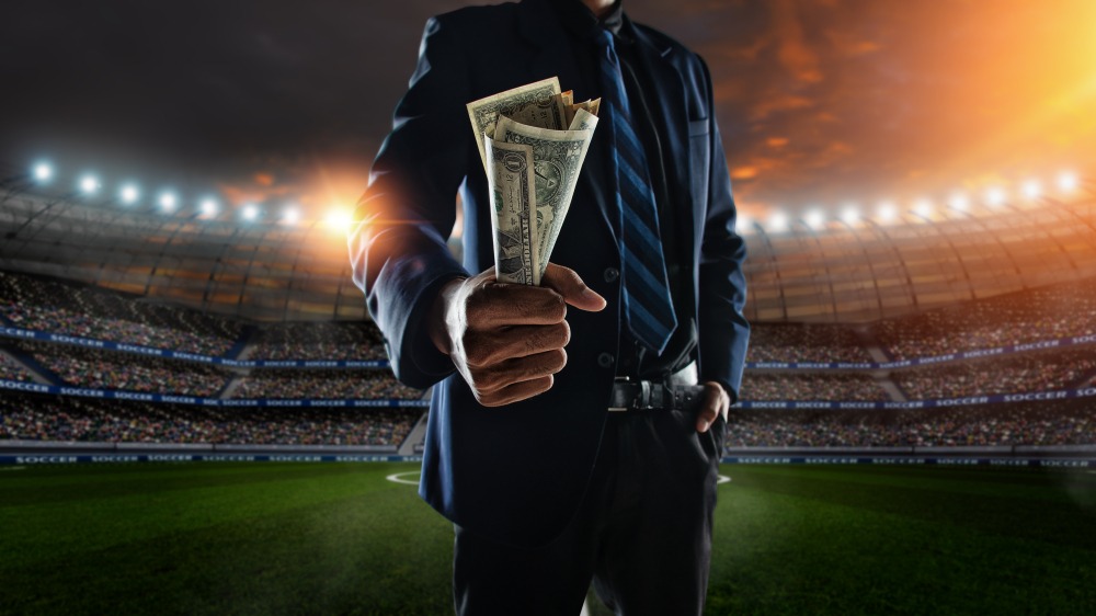 businessman,holding,large,amount,of,bills,at,soccer,stadium,in